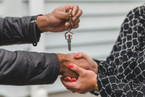 Real estate agent shaking hands with client and handing over keys